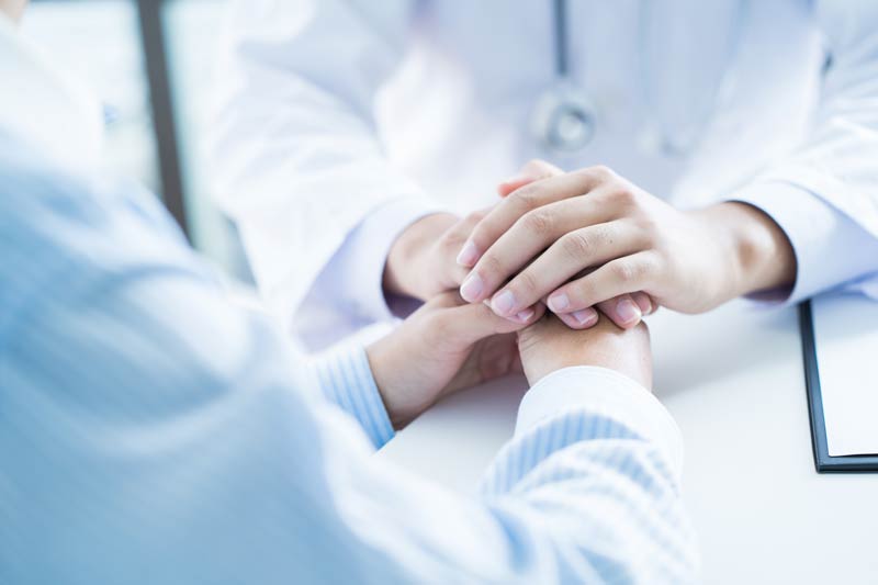 A caring hand holding a patient's hand